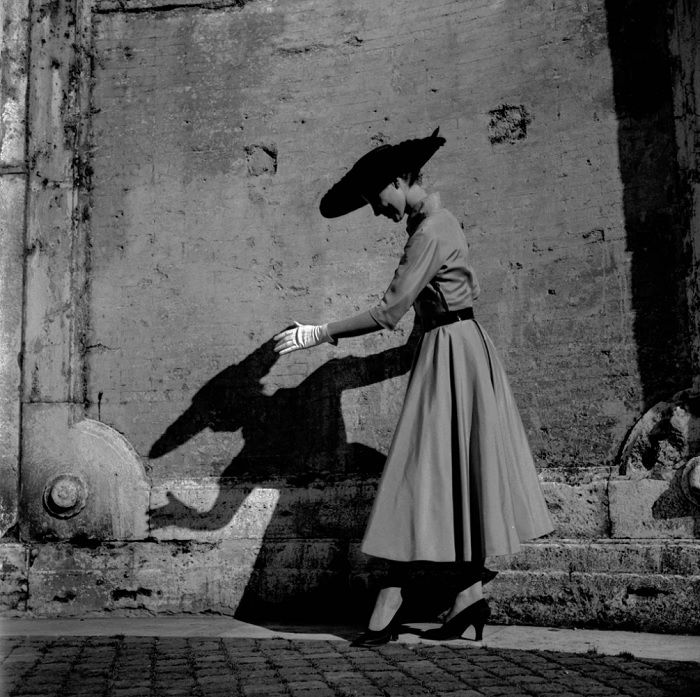 Woman in hat with long shadow on the wall