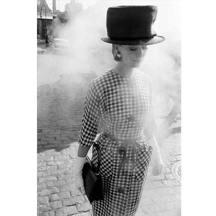 Woman in big hat walking through street smoke