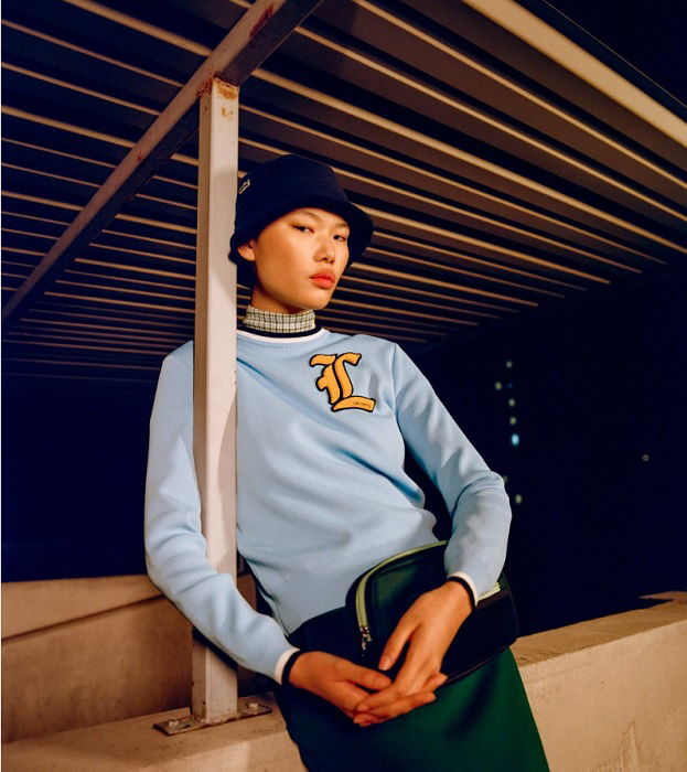 Young man in blue jumper leaning against pole